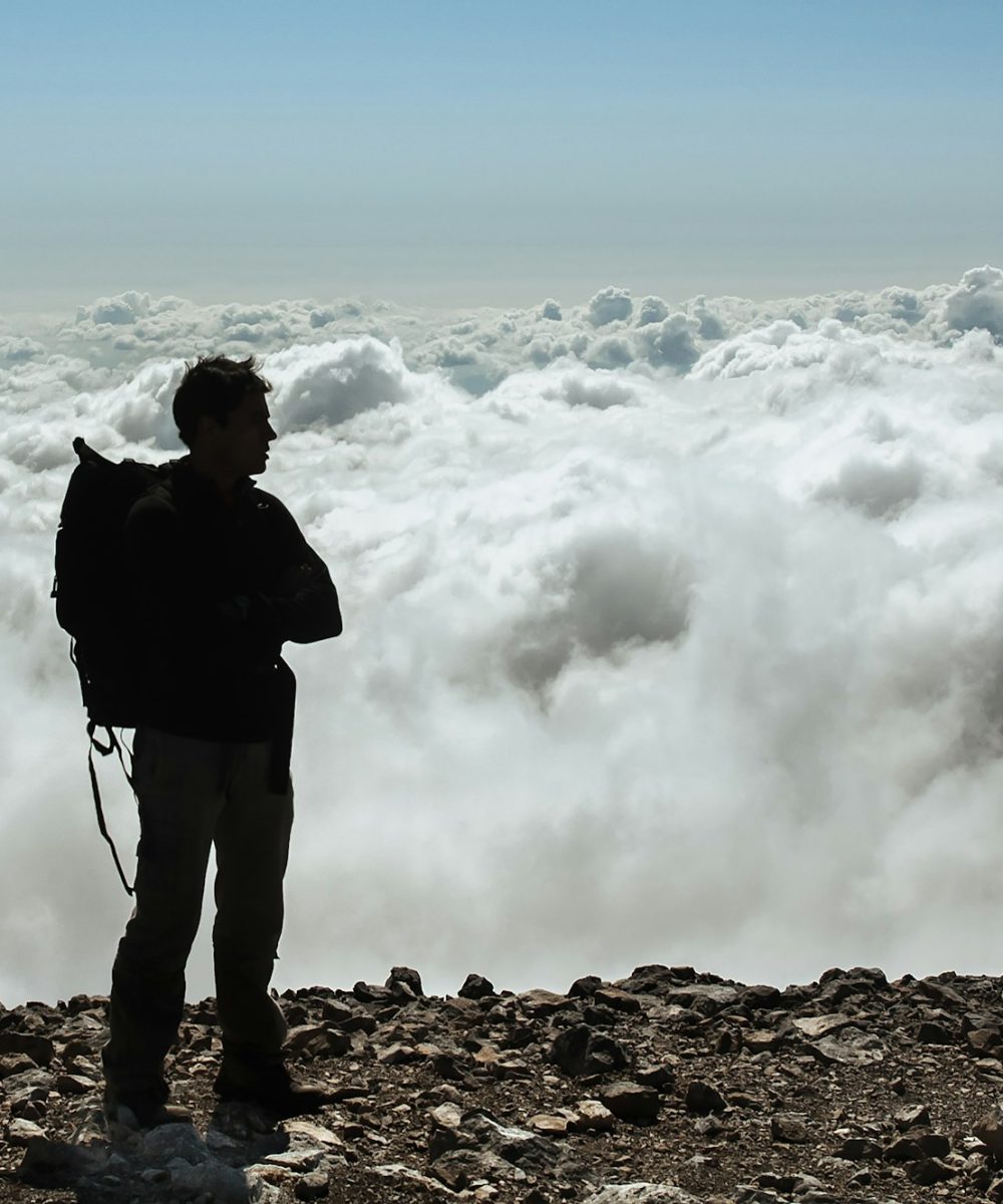 Male standing on the summit of a mountain peak Male standing on the summit of a mountain peak